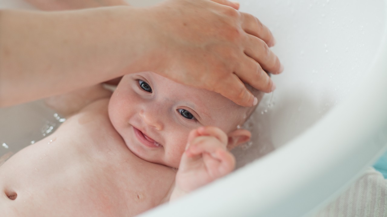 El Primer Baño Del Bebé Recién Nacido Girl.The Madre Lava El Bebé