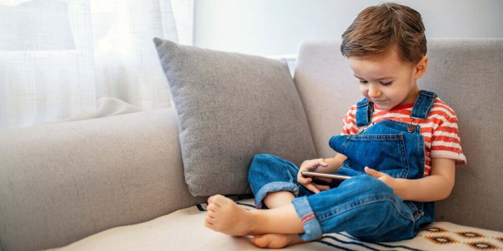 Niño usando una tableta junto a su madre, promoviendo el uso responsable de pantallas.