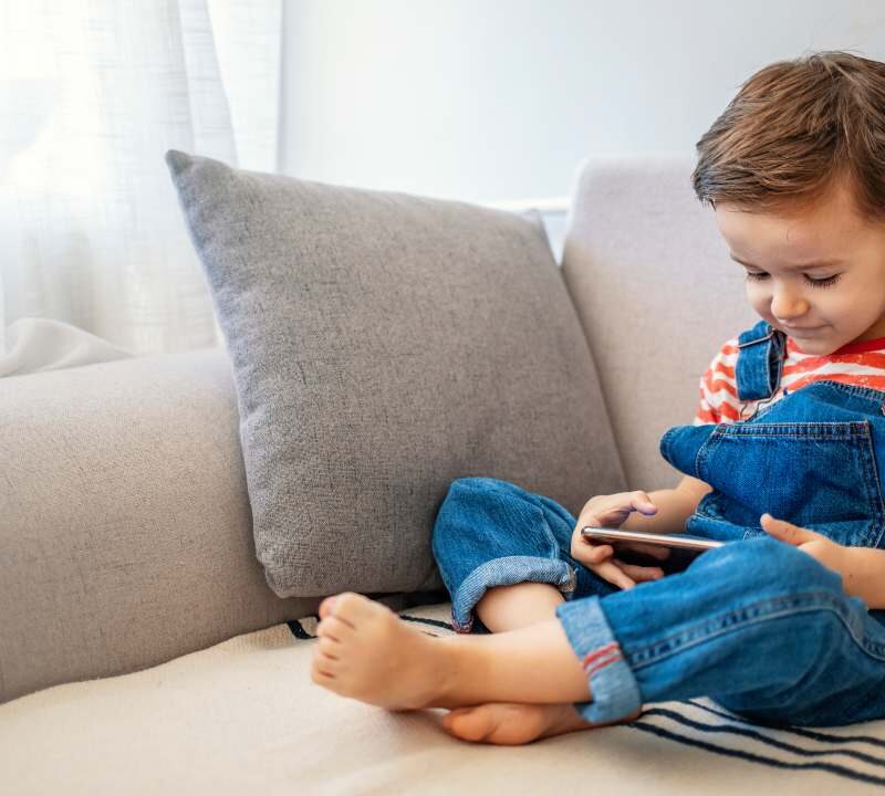 Niño usando una tableta junto a su madre, promoviendo el uso responsable de pantallas.