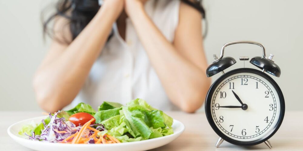 Persona mirando el reloj mientras prepara una ensalada durante su ventana de alimentación