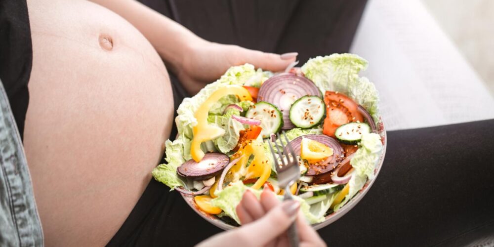 mujer embarazada feliz comiendo comida vegana saludable