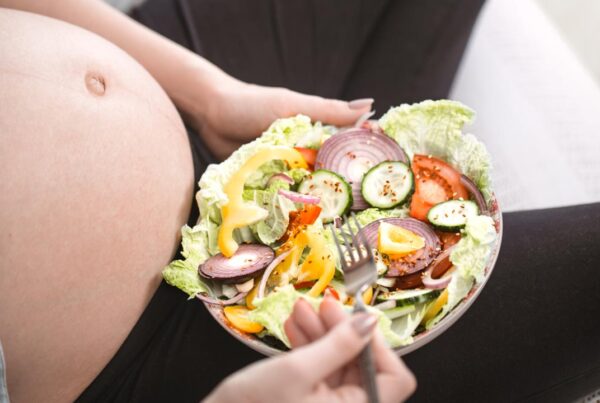 mujer embarazada feliz comiendo comida vegana saludable