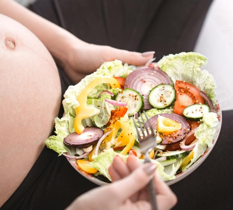 mujer embarazada feliz comiendo comida vegana saludable