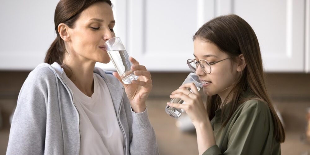 Mujer bebiendo agua para cumplir con la recomendación de beber dos litros de agua al día.