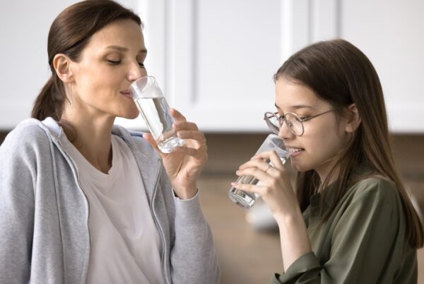 Mujer bebiendo agua para cumplir con la recomendación de beber dos litros de agua al día.