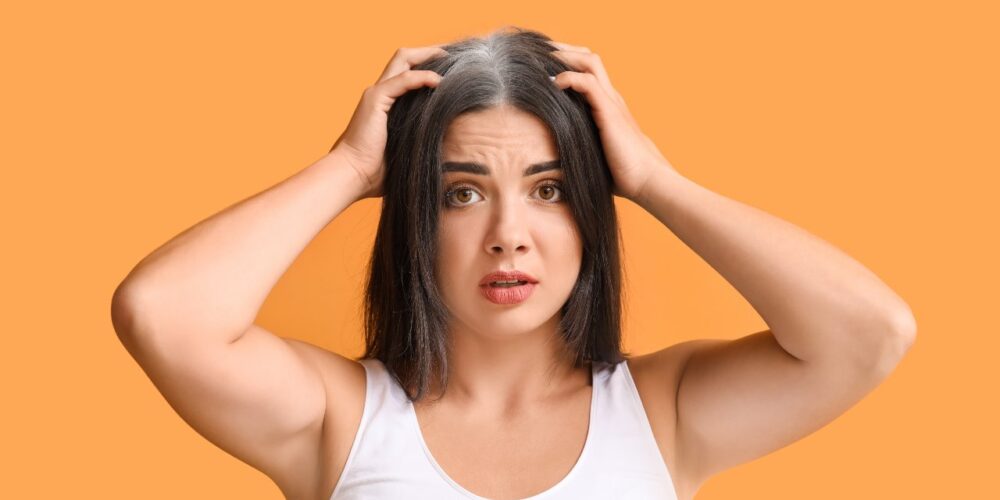 Mujer joven con canas visibles en la línea frontal del cabello