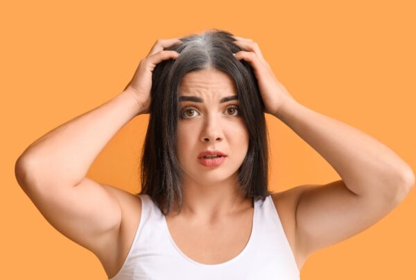Mujer joven con canas visibles en la línea frontal del cabello