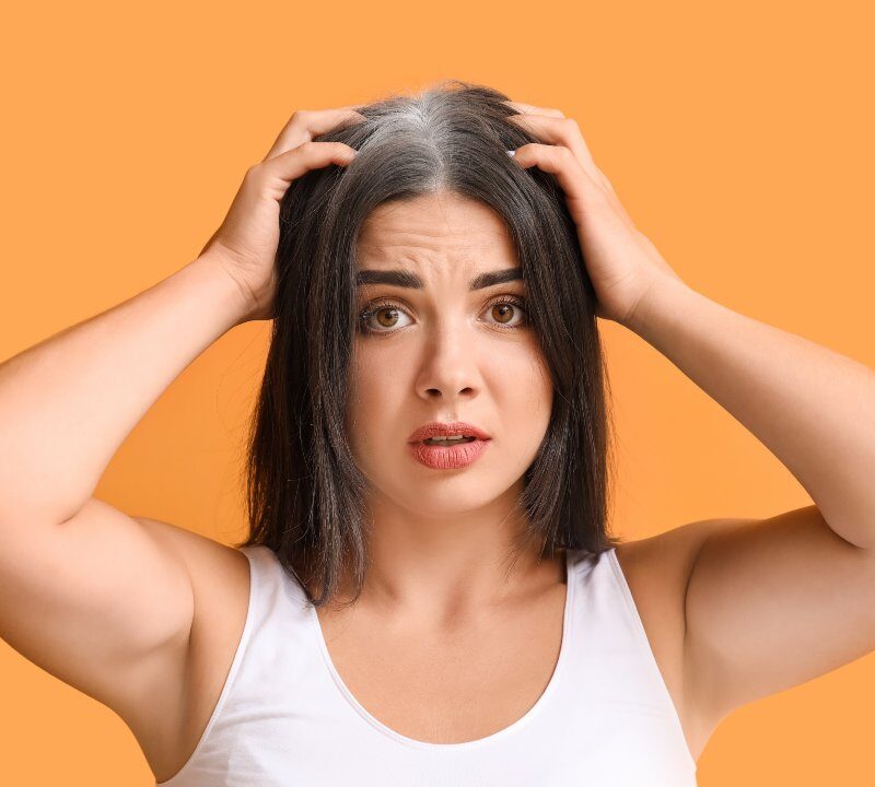 Mujer joven con canas visibles en la línea frontal del cabello