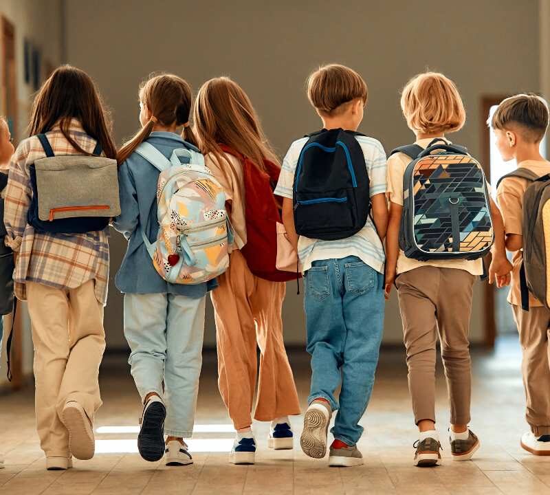 Niños con mochila escolar ergonómica correctamente colocada