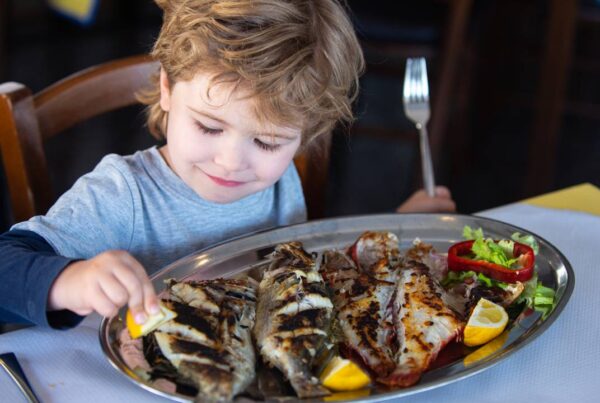 Niño comiendo pescado rico en omega-3 como protección contra la miopía.