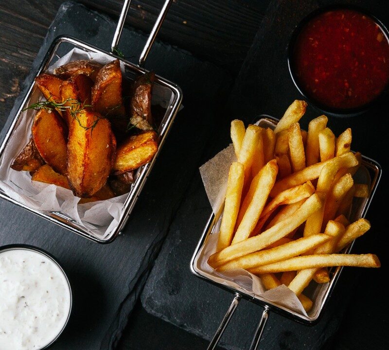 Papas fritas servidas en bandeja con fondo oscuro