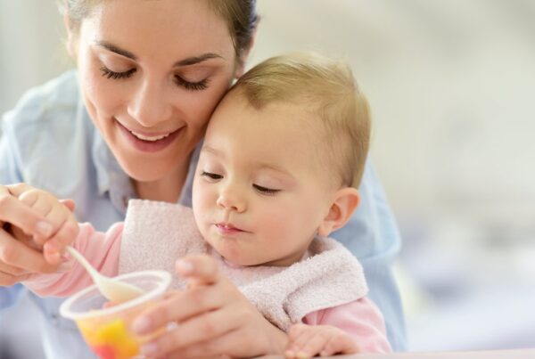 Madre alimentando a su bebé con frutas en casa mientras juegan 