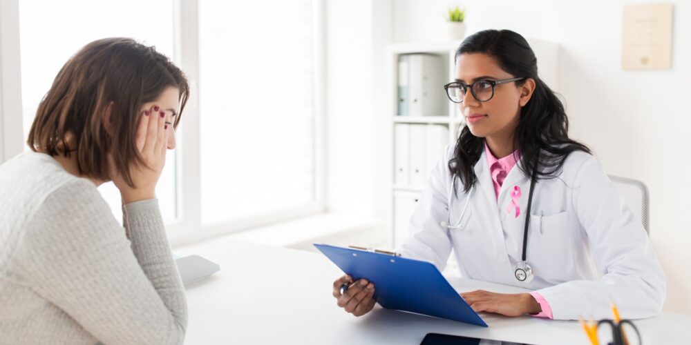 Médico explicando nuevos tratamientos para el cáncer de mama avanzado a una paciente.