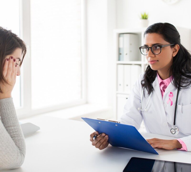 Médico explicando nuevos tratamientos para el cáncer de mama avanzado a una paciente.