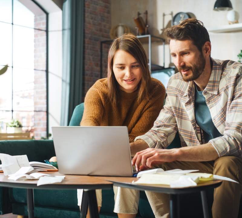 Pareja revisando sus gastos diarios y calculando en una libreta o app financiera.