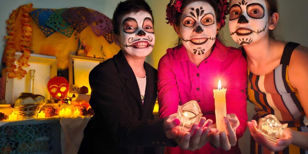 Familia sonriendo abrazados con decoración de Halloween y Día de Muertos en casa.