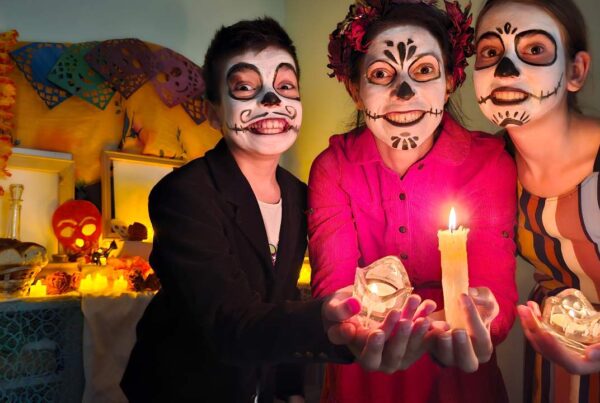 Familia sonriendo abrazados con decoración de Halloween y Día de Muertos en casa.