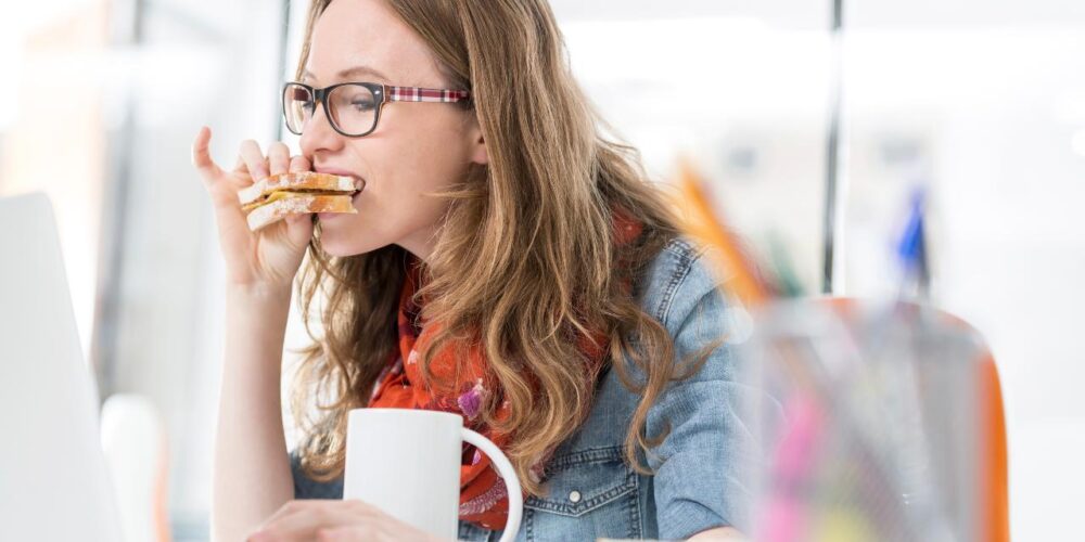 Mujer comiendo con prisa frente al ordenador