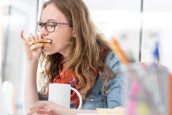 Mujer comiendo con prisa frente al ordenador
