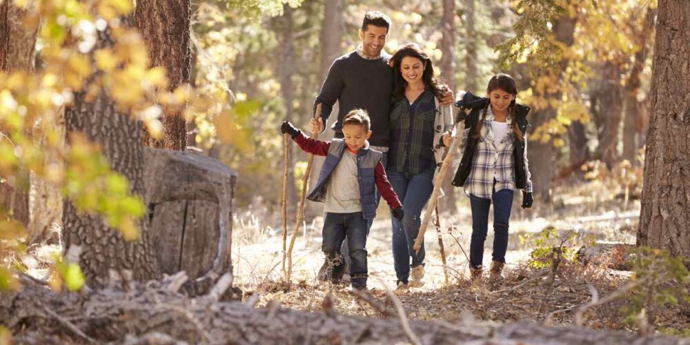 Familia con niños interactuando con la naturaleza, representando hábitos sencillos de crianza ecológica para criar hijos más conscientes.