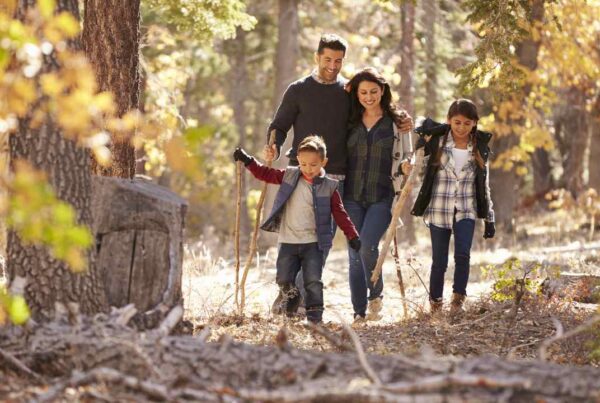 Familia con niños interactuando con la naturaleza, representando hábitos sencillos de crianza ecológica para criar hijos más conscientes.