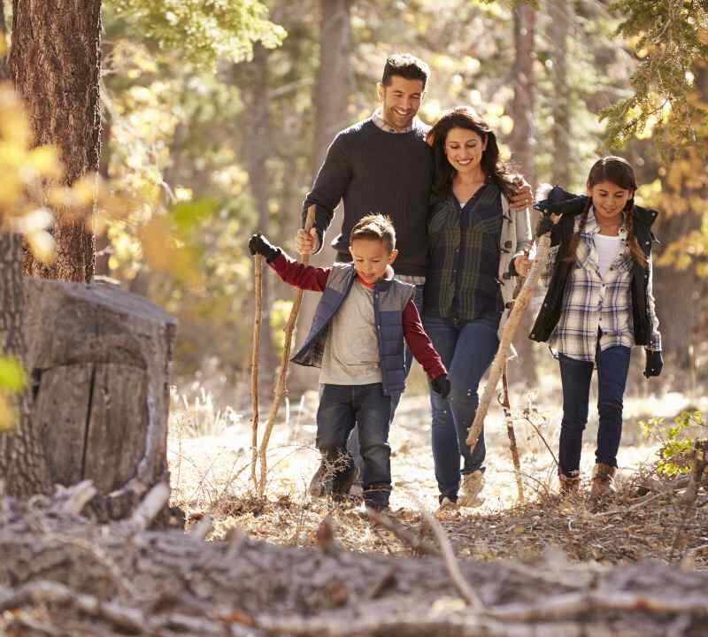 Familia con niños interactuando con la naturaleza, representando hábitos sencillos de crianza ecológica para criar hijos más conscientes.