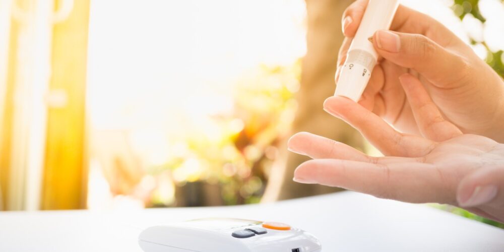 Persona revisando su nivel de azúcar en la sangre con un glucómetro, representando el control de la diabetes.
