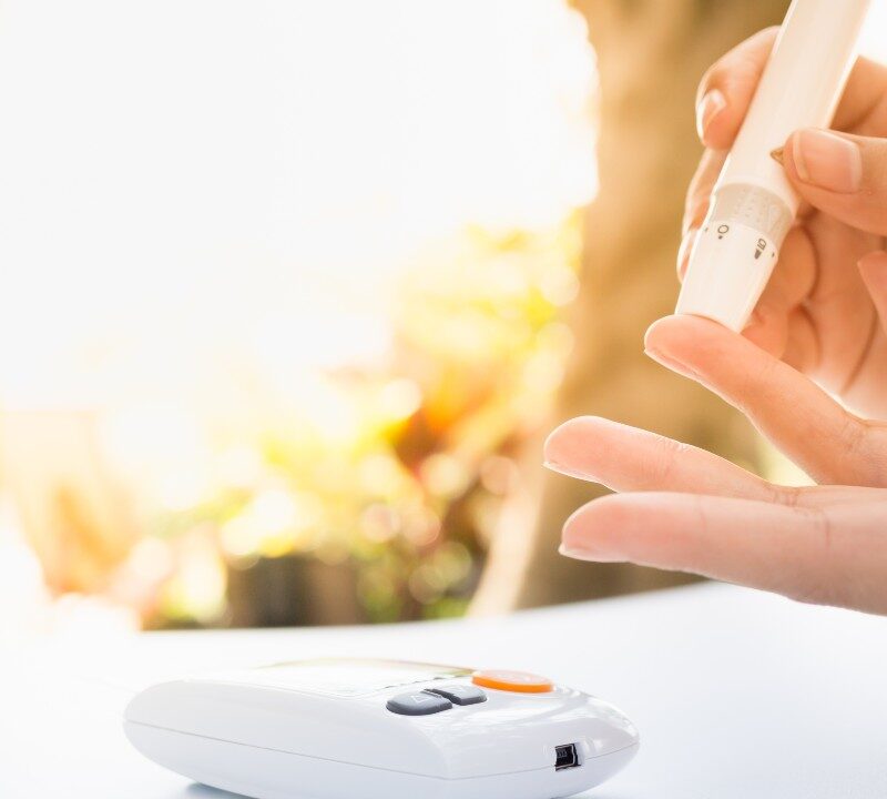Persona revisando su nivel de azúcar en la sangre con un glucómetro, representando el control de la diabetes.