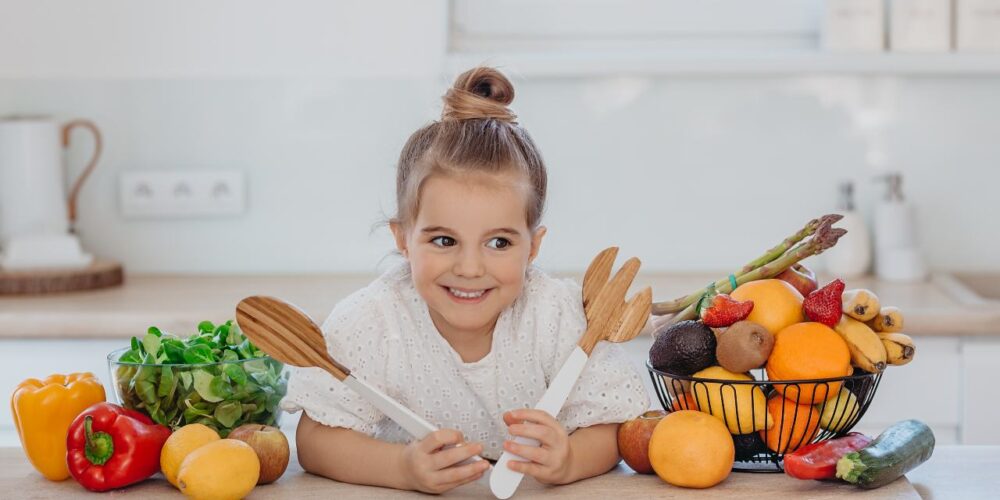 Niños comiendo variedad de frutas y verduras representando dietas vegetarianas y veganas
