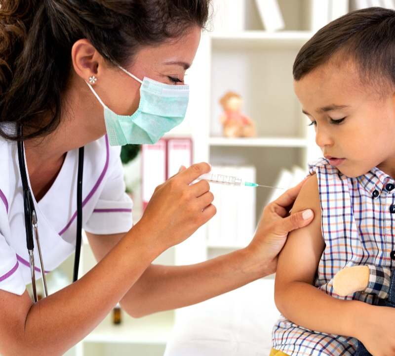 Profesional de la salud aplicando una vacuna a un niño pequeño para prevenir los casos de sarampión.