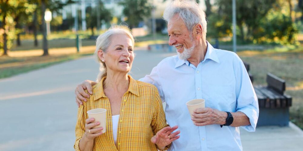 Pareja mayor caminando junta al aire libre y conversando
