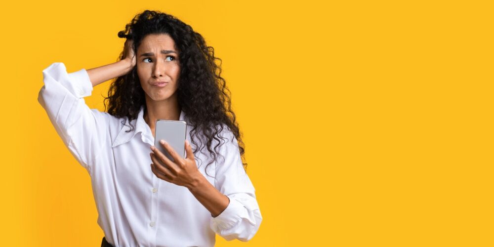 Persona mirando su teléfono móvil con expresión de duda, representando la confusión entre hábito y adicción a las redes sociales.