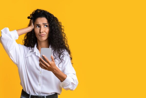 Persona mirando su teléfono móvil con expresión de duda, representando la confusión entre hábito y adicción a las redes sociales.