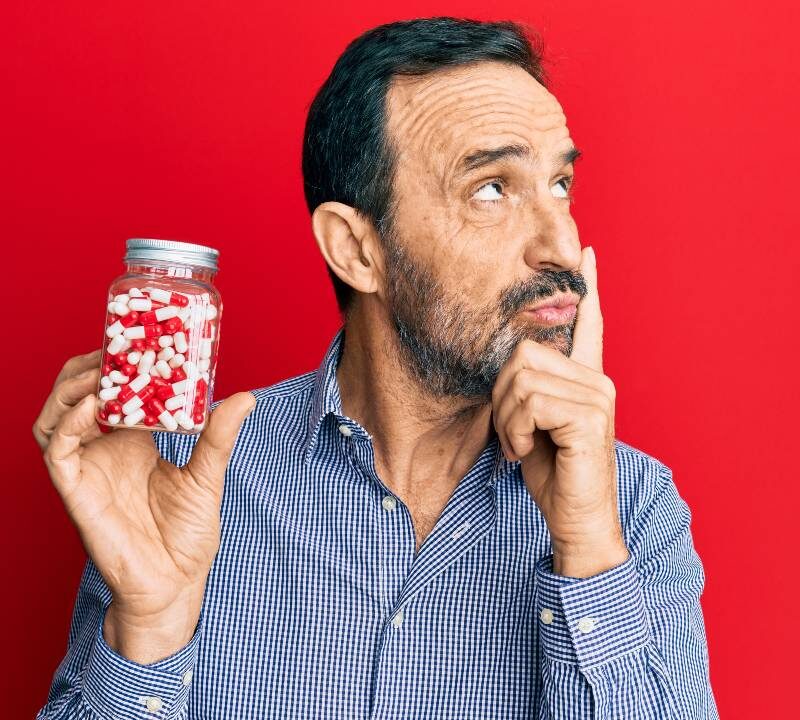 Persona sosteniendo un frasco de pastillas con gesto de reflexión, simbolizando la decisión de dejar los antidepresivos.