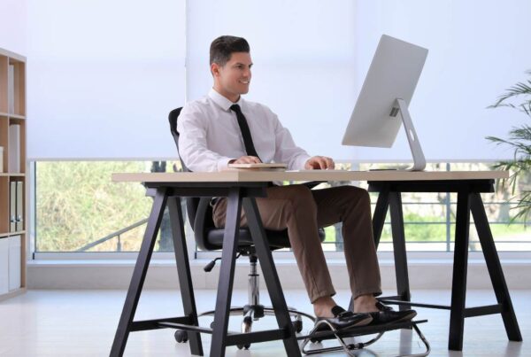 Persona trabajando en oficina con postura correcta para proteger huesos y articulaciones