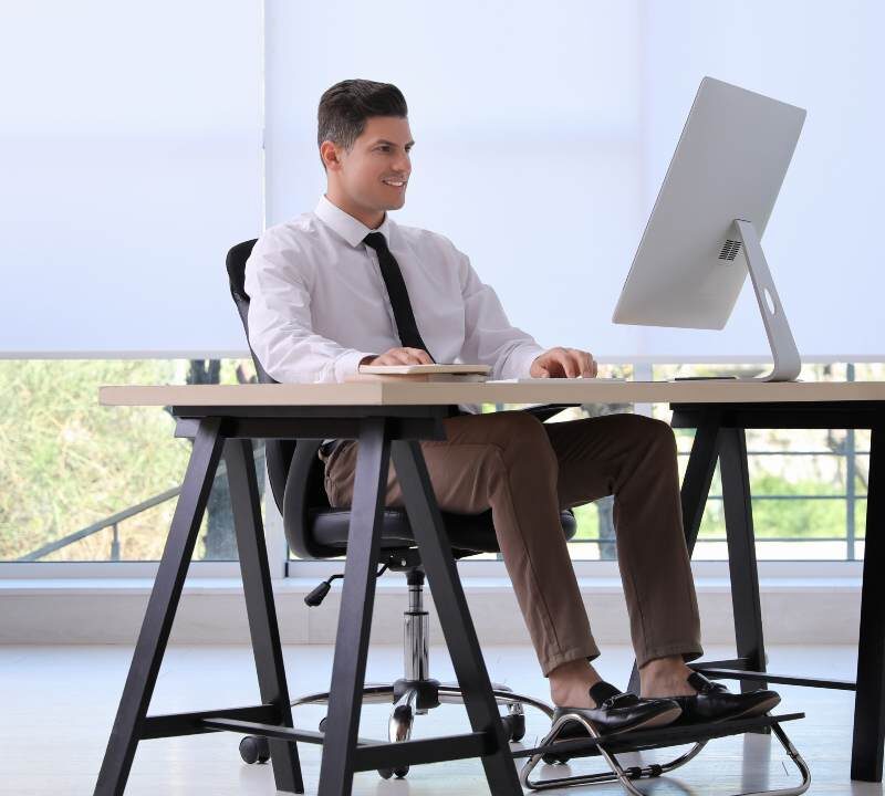 Persona trabajando en oficina con postura correcta para proteger huesos y articulaciones