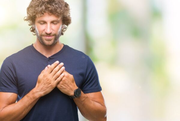 Persona practicando meditación de amor benevolente con expresión de calma y manos sobre el pecho.