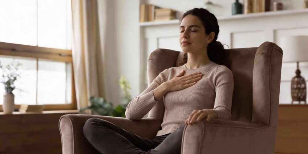 Mujer practicando meditación de amor benevolente con una mano en el corazón.