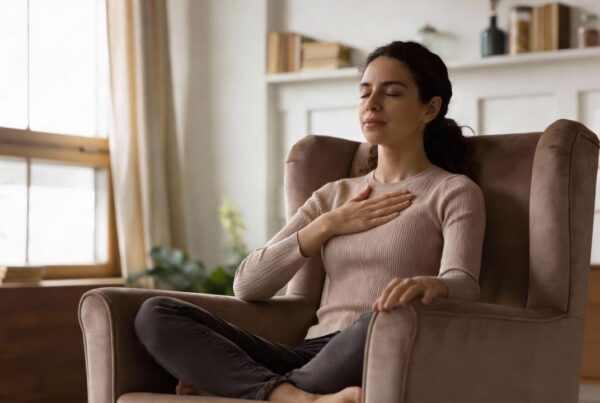 Mujer practicando meditación de amor benevolente con una mano en el corazón.