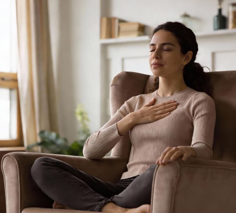 Mujer practicando meditación de amor benevolente con una mano en el corazón.