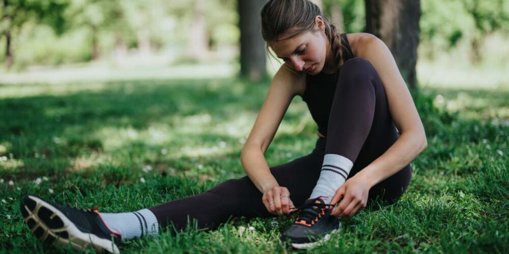 Mujer joven atándose las agujetas de los tenis para salir a correr como terapia contra la depresión.