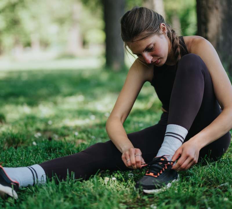 Mujer joven atándose las agujetas de los tenis para salir a correr como terapia contra la depresión.