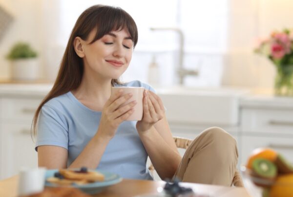 Persona sonriente sosteniendo una taza humeante, ilustrando los beneficios del consumo de café en la salud mental.