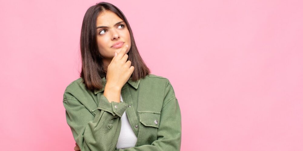 Mujer joven pensativa representando la salud hormonal y la prevención del cáncer.