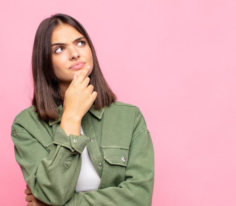 Mujer joven pensativa representando la salud hormonal y la prevención del cáncer.