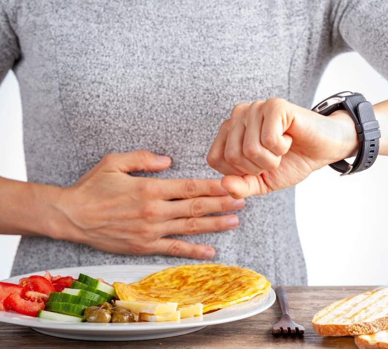 Mujer mirando el reloj antes de comer durante ayuno intermitente