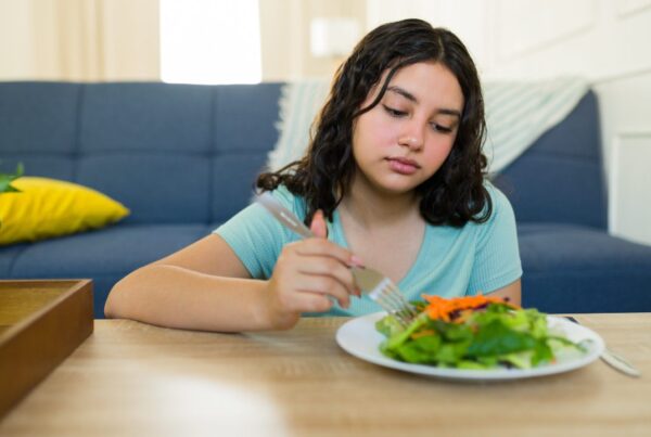 Mujer preocupada frente a un plato de comida, representando los efectos de las dietas muy bajas en calorías en el metabolismo y la salud mental