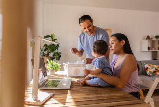 Pareja trabajando desde casa con su bebé mientras usan una computadora portátil