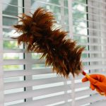 Persona limpiando el polvo y ventilando una habitación para mejorar la calidad del aire en casa