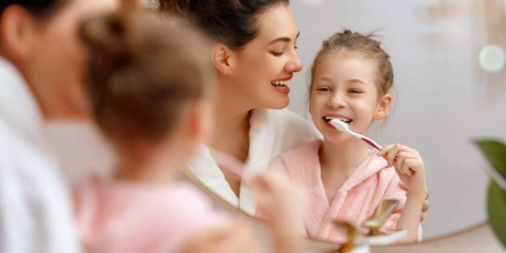 Niño cepillándose los dientes con supervisión de un adulto